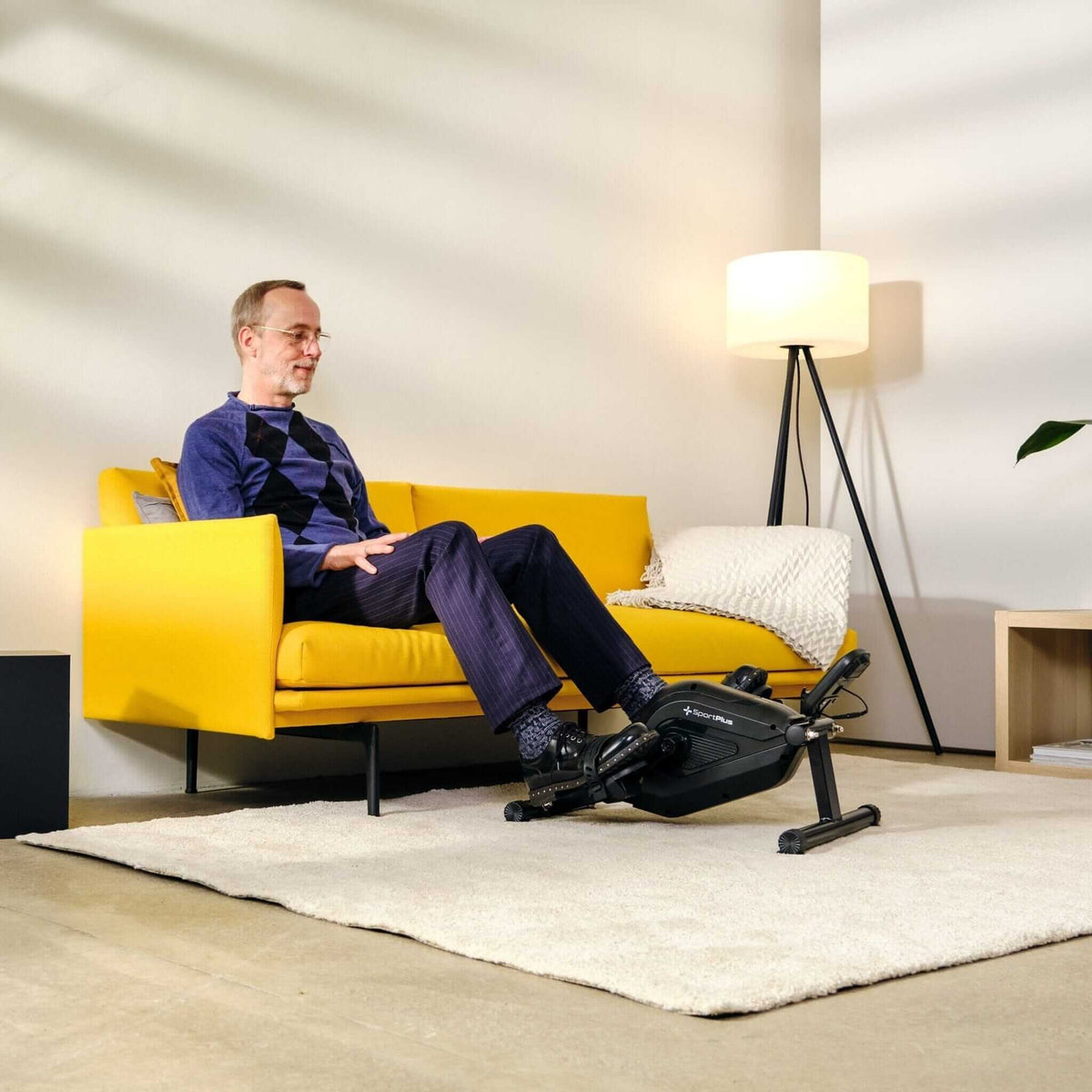 Alt Tag: Mini Heimtrainer Beintrainer mit App-Kompatibilität im Sitzen nutzen – leiser Beintrainer mit Magnetbremse im Wohnzimmer