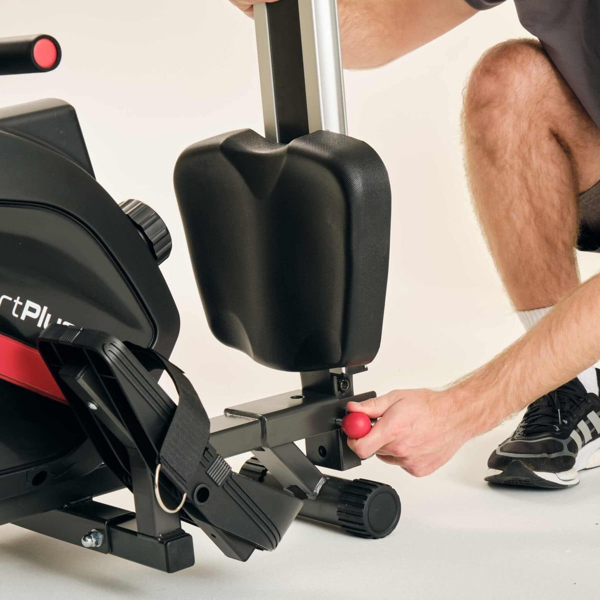 Rudergerät klappbar – Person klappt das Heimtrainer-Rudergerät zusammen, zeigt Transportrolle und Magnetwiderstand für leises Training