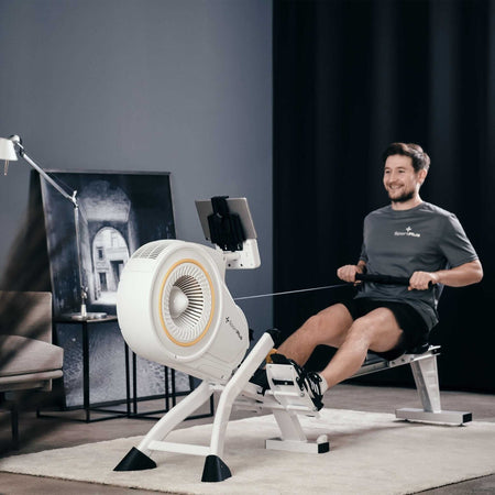 Alt Tag: Rudergerät mit Luftwiderstand und App-Kompatibilität im Home-Gym, Mann beim Training am Turbinen-Rudergerät mit Tablet-Halterung