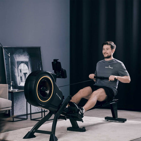 Rudergerät mit Luftwiderstand und App-Kompatibilität im Homegym, Mann beim Rudern am Turbinen-Luftwiderstandsgerät